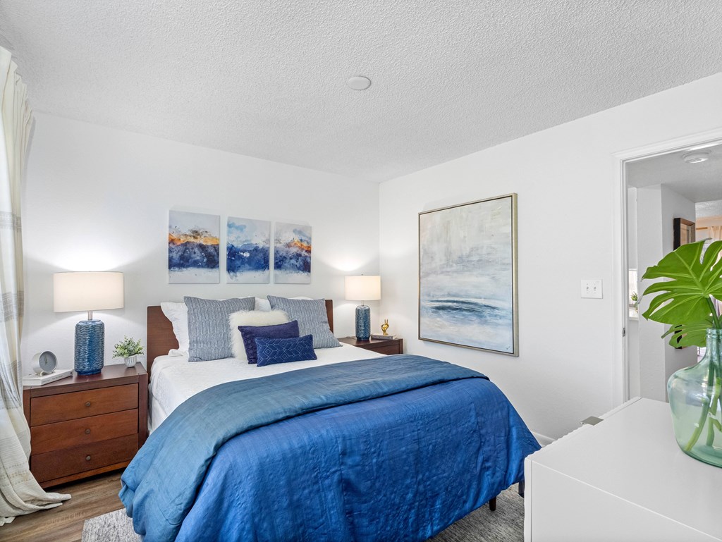 A bedroom with a large bed and a painting on the wall.